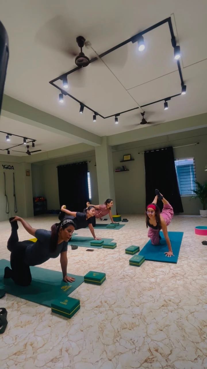The practice hall at Paathway2Yoga studio, Ulubari, Guwahati, with sage green walls, mirrors and track lighting during a group class